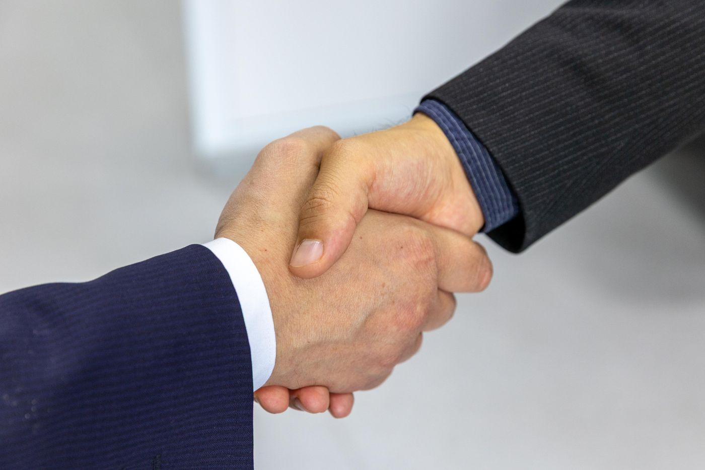 Two people shaking hands across a table in a business meeting