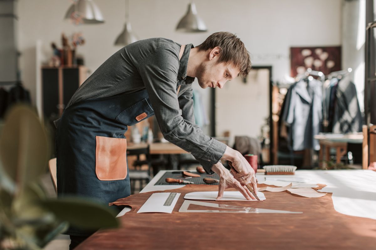 Craftsman working leather at his bench in a small studio