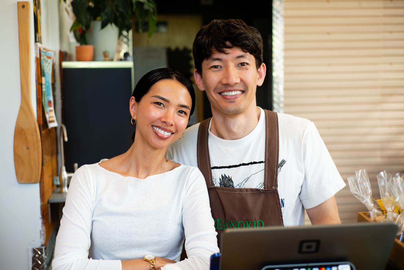 Two cafe owners standing together behind their counter