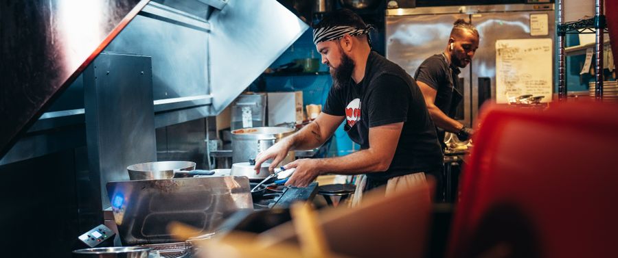 Two chefs preparing dishes in a busy restaurant kitchen