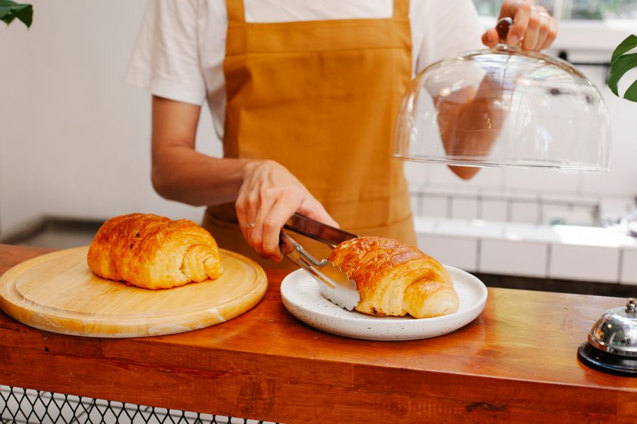 Baker plating fresh pastries behind a cafe counter